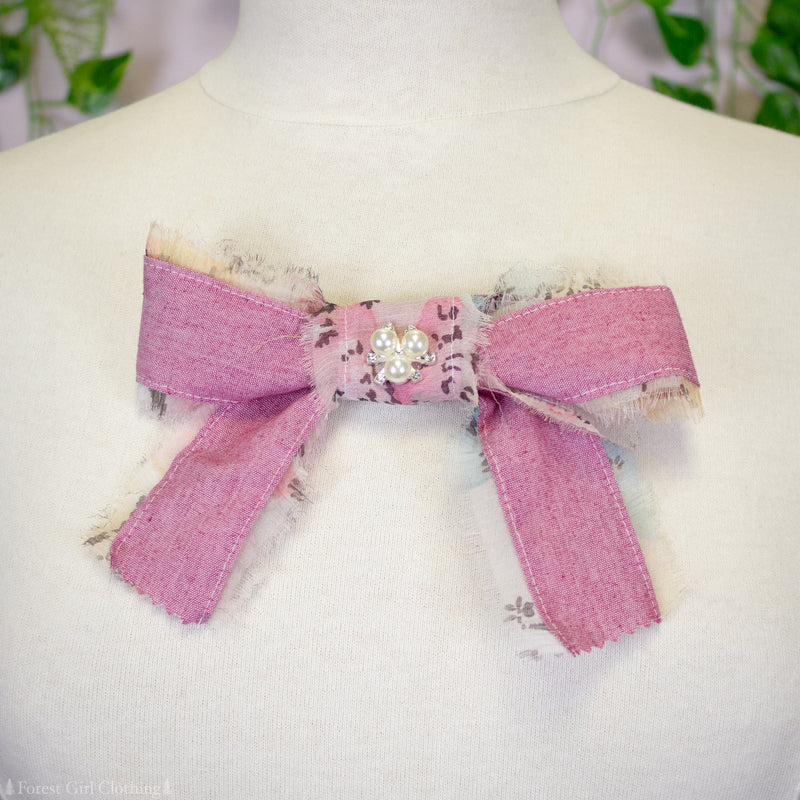 Pink fabric bow with a decorative center on a mannequin.